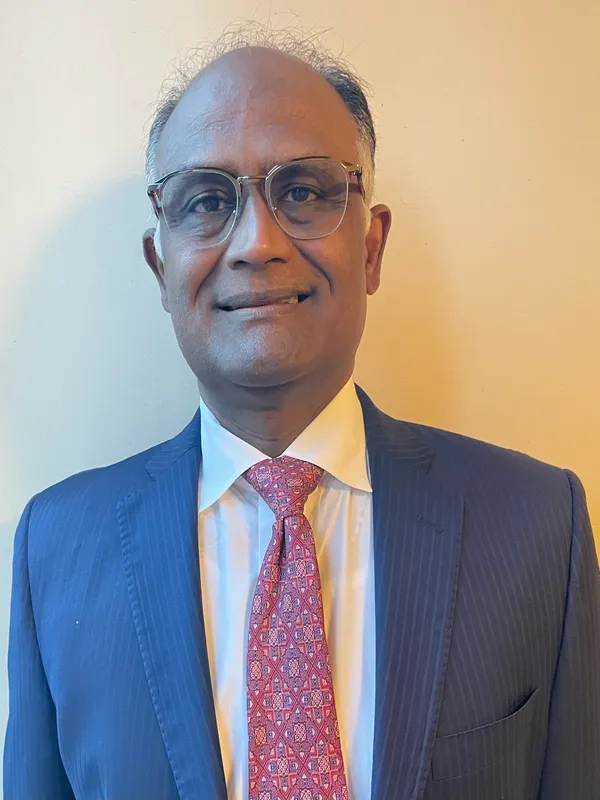 A man in a suit and tie standing next to a wall.